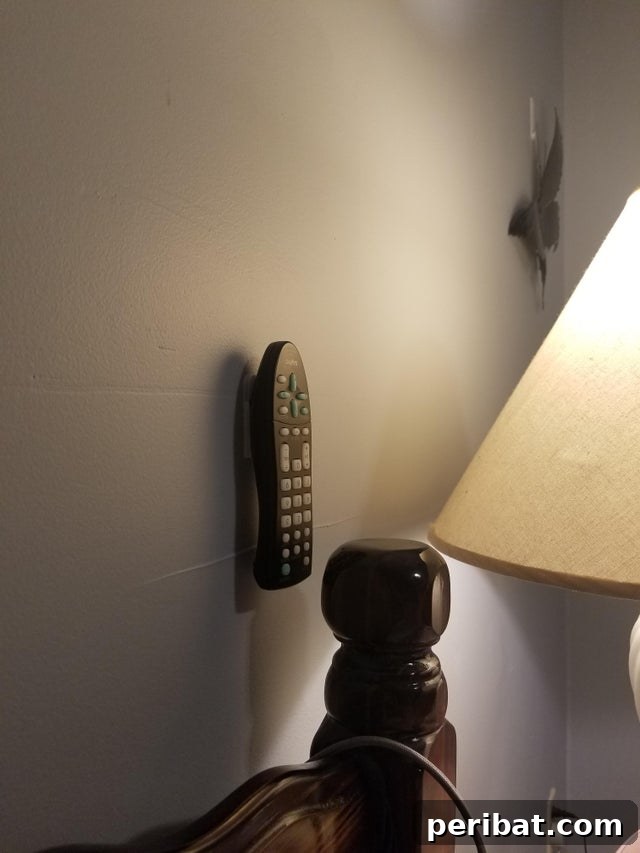 The Ultimate Command Strip Guide 75 Ingenious Uses and Application Tips 12 Remote control attached to a wall with a Command Strip for easy access.