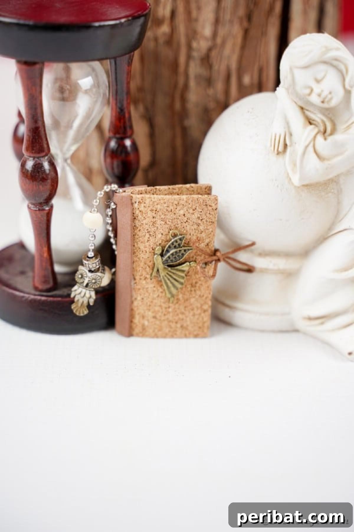Mini book keychain laening against an hourglass