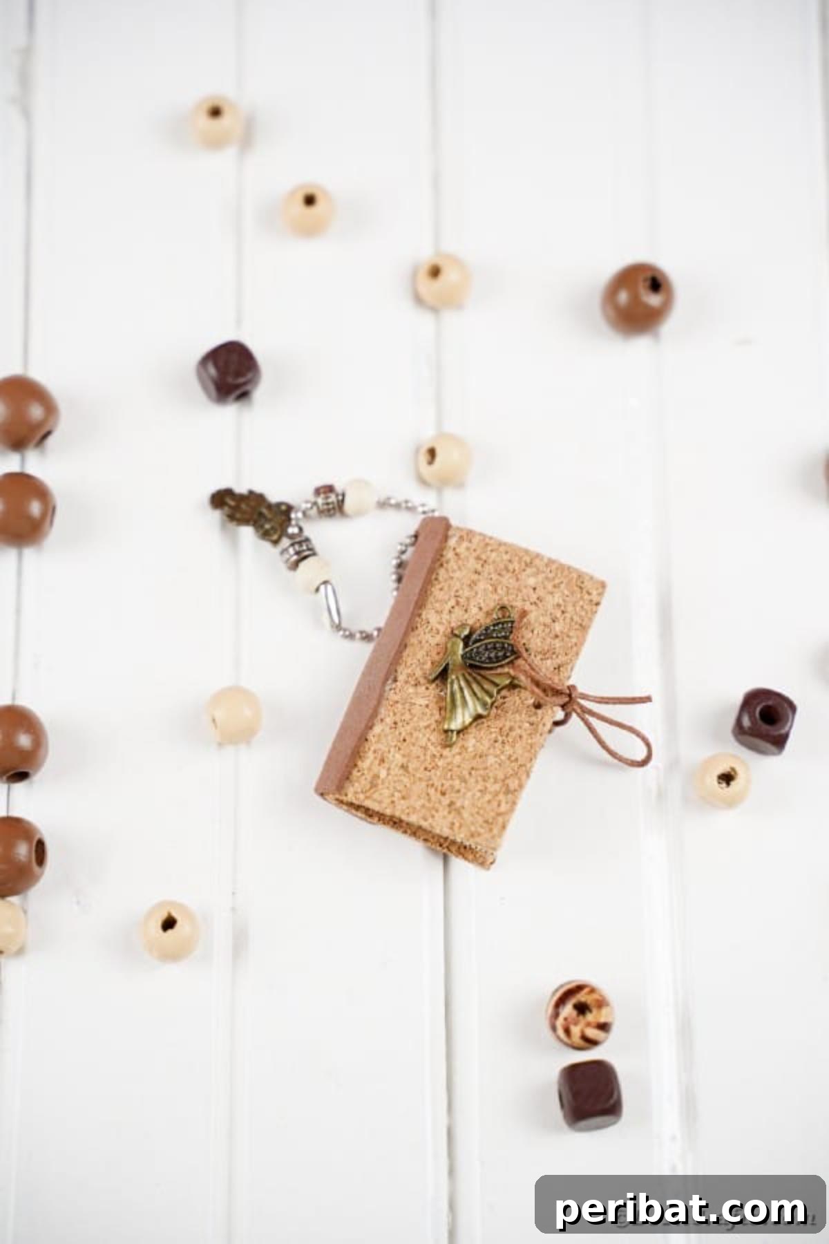 Miniature book keychain on white table with wooden beads