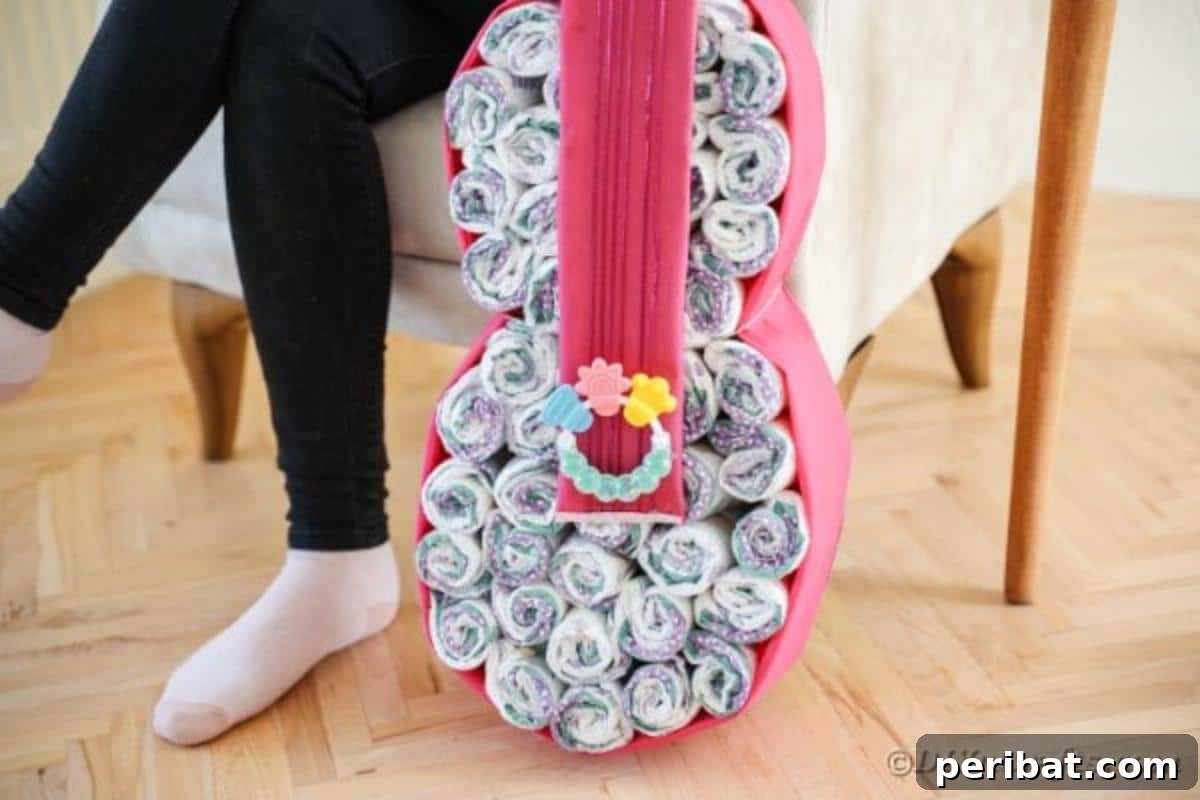 A person working on the guitar diaper cake, with completed sections visible