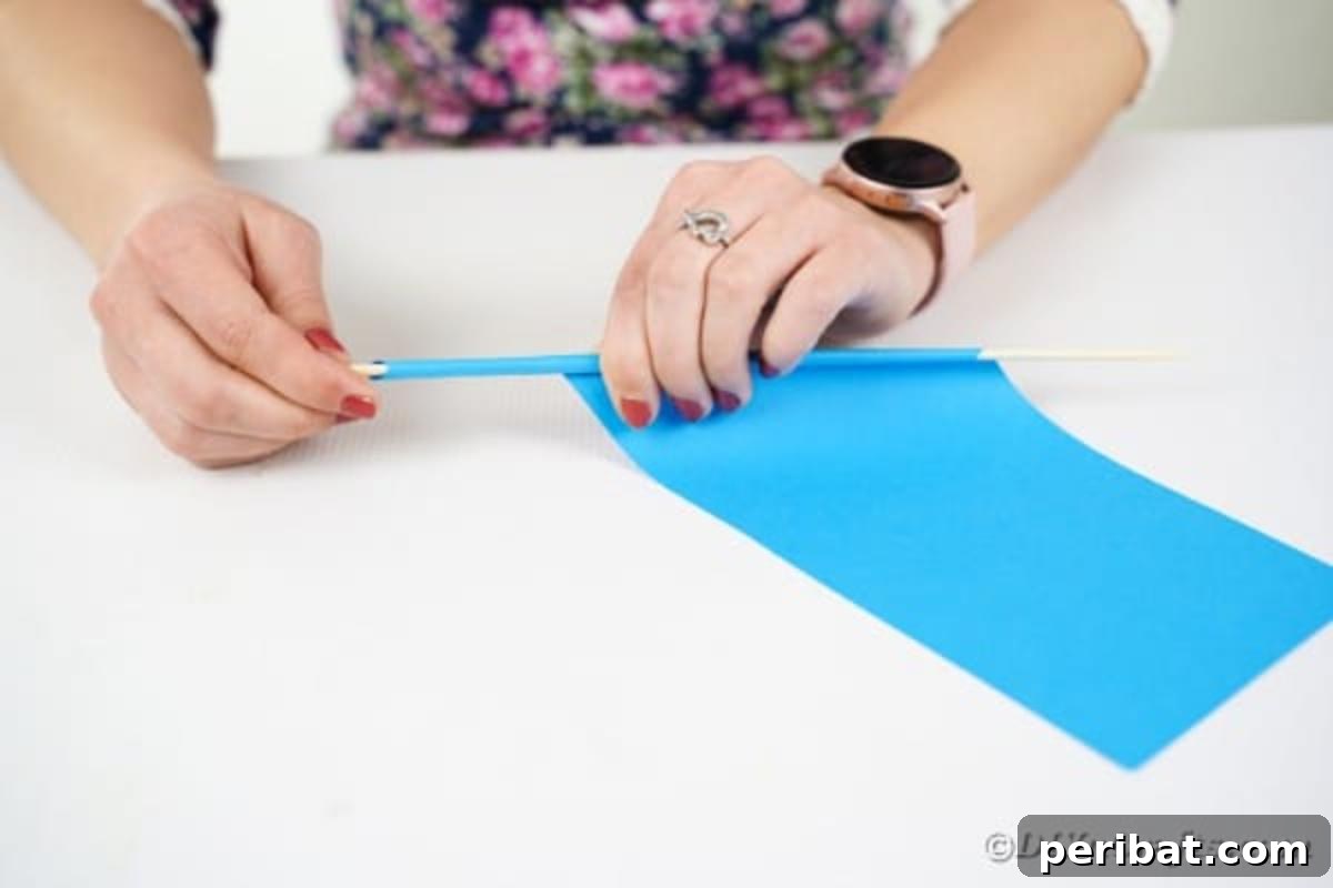 Rolling paper around a dowel to create a paper straw