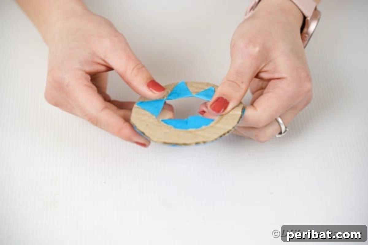 Coating a cardboard ring with blue paper, leaving the center open