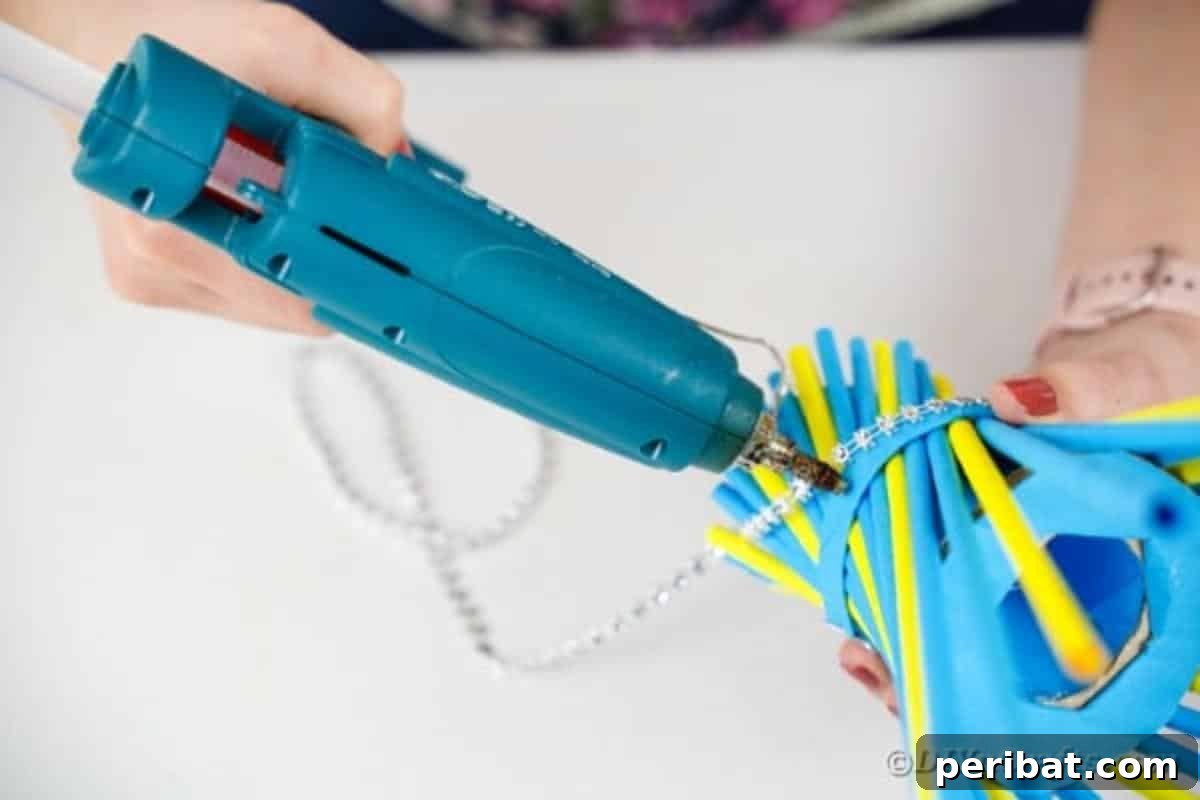 Gluing a decorative beaded ribbon around the vase's mid-section