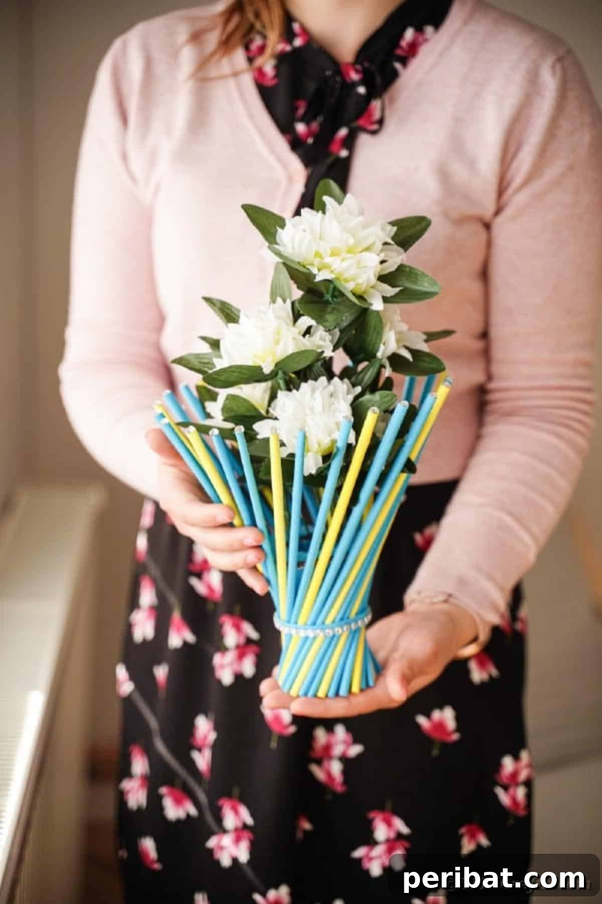Finished twisted paper straw vase with artificial flowers, held by a woman