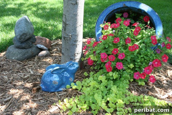Cascading Flower Pot Art for Stunning Garden Decor 4 A large rustic bucket overflowing with bright red flowers, nestled beside a tree, creating a whimsical fairy garden scene with a tower of rocks and a ceramic bunny.