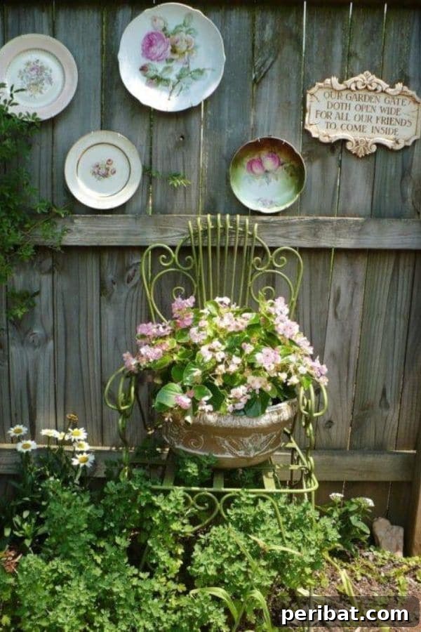 32 DIY Vintage Garden Crafts to Add Rustic Charm 3 Old wire-frame chair against a wooden fence, adorned with a planter of pink flowers and antique decorative plates.