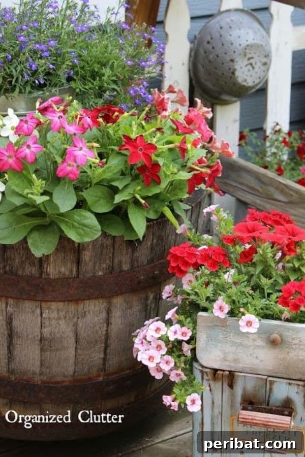 32 DIY Vintage Garden Crafts to Add Rustic Charm 4 Antique ice cream freezer repurposed as a planter with vibrant red flowers, next to a whiskey barrel planter.