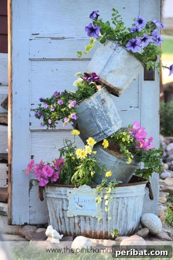 32 DIY Vintage Garden Crafts to Add Rustic Charm 7 A creative tipsy planter arrangement using stacked galvanized buckets filled with colorful flowers.
