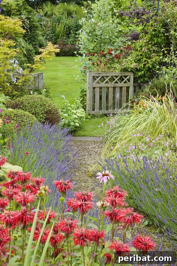A beautiful winding garden path made of natural stones, bordered by an array of colorful red flowers and diverse shrubs