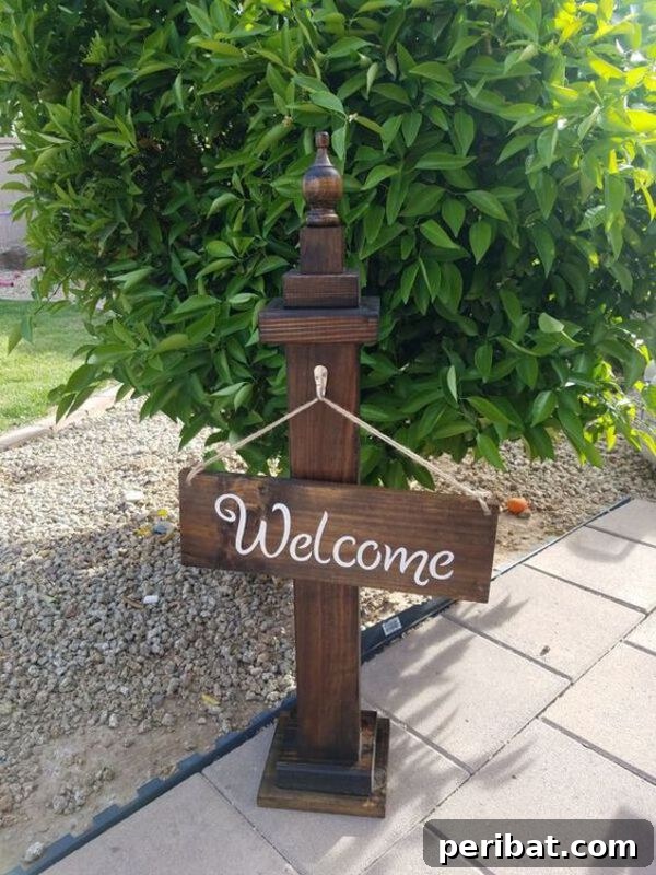 Wooden welcome sign hanging from a small wooden pedestal