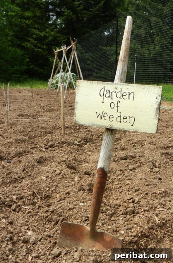 Garden sign made from an old shovel with a wooden plaque reading 'Garden of Weeden'