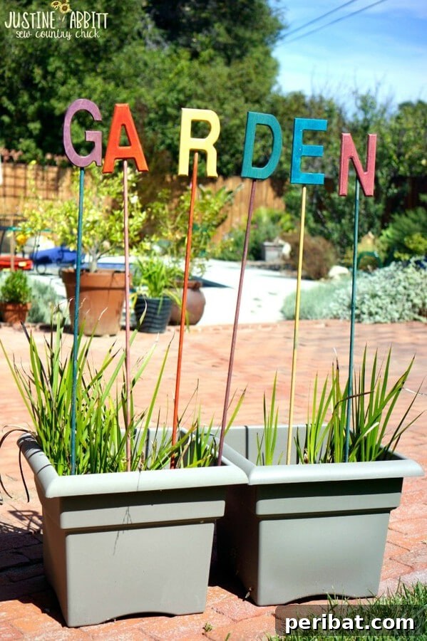 Individual painted letters spelling out 'garden' on stakes in a garden bed