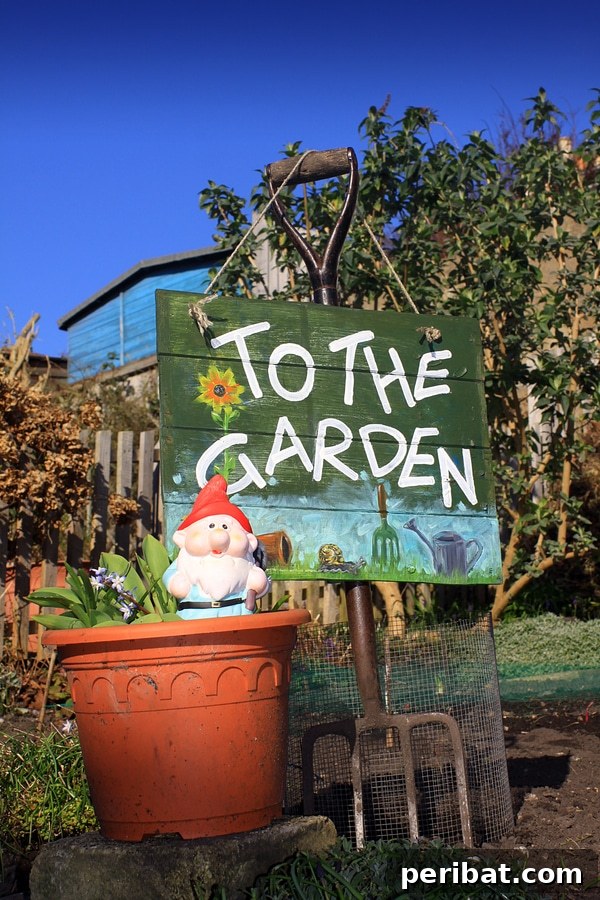 Painted wooden sign pointing 'To the Garden' propped against a garden fork