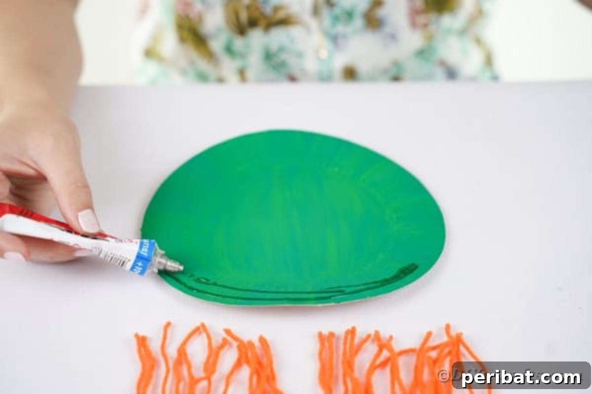 Spooktacular Paper Plate Witch Craft 13 Applying glue to the top edge of the painted paper plate