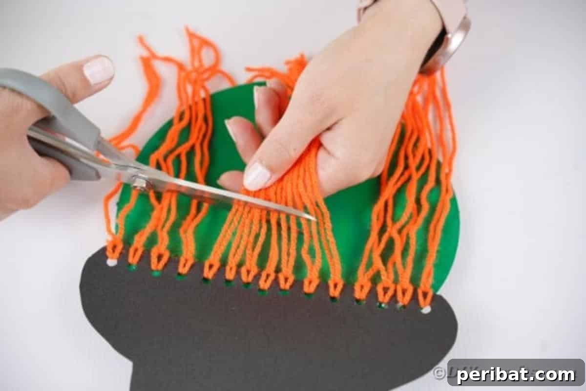 Spooktacular Paper Plate Witch Craft 15 Trimming the yarn hair to create bangs on the paper plate witch