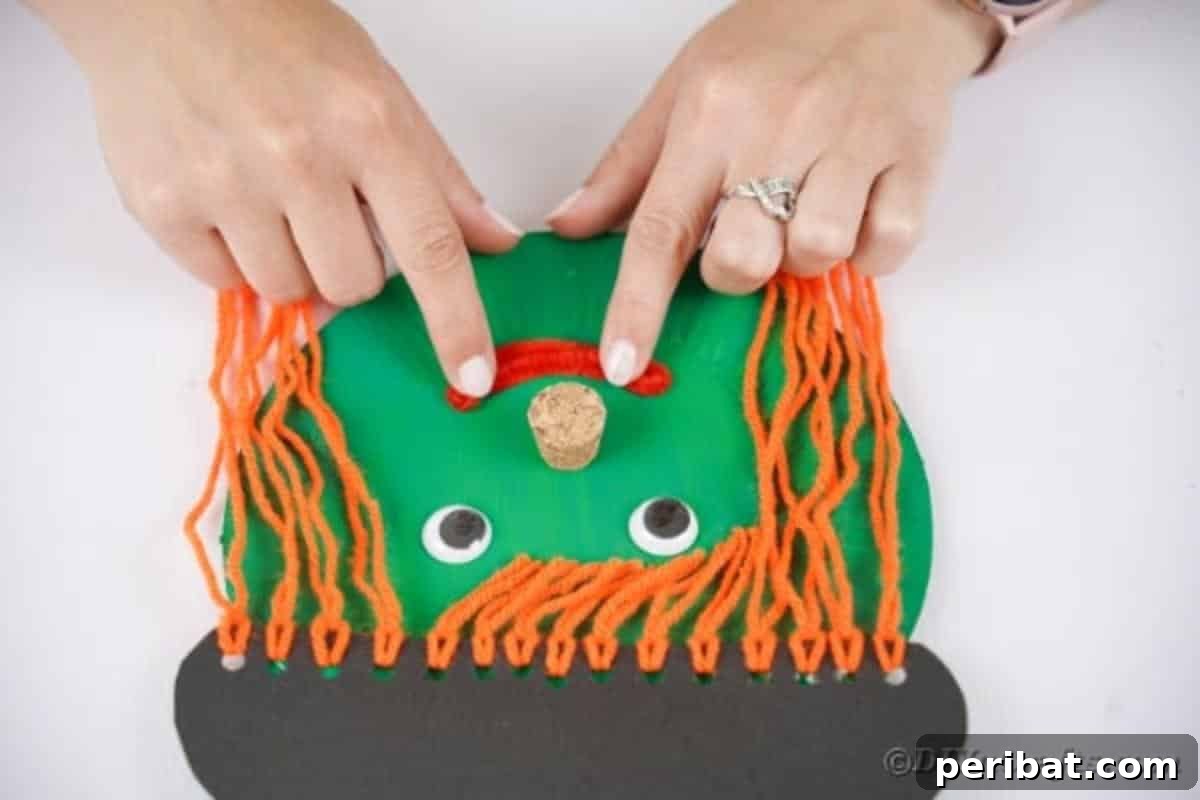 Spooktacular Paper Plate Witch Craft 18 Gluing a red pipe cleaner bent into a smile onto the witch face
