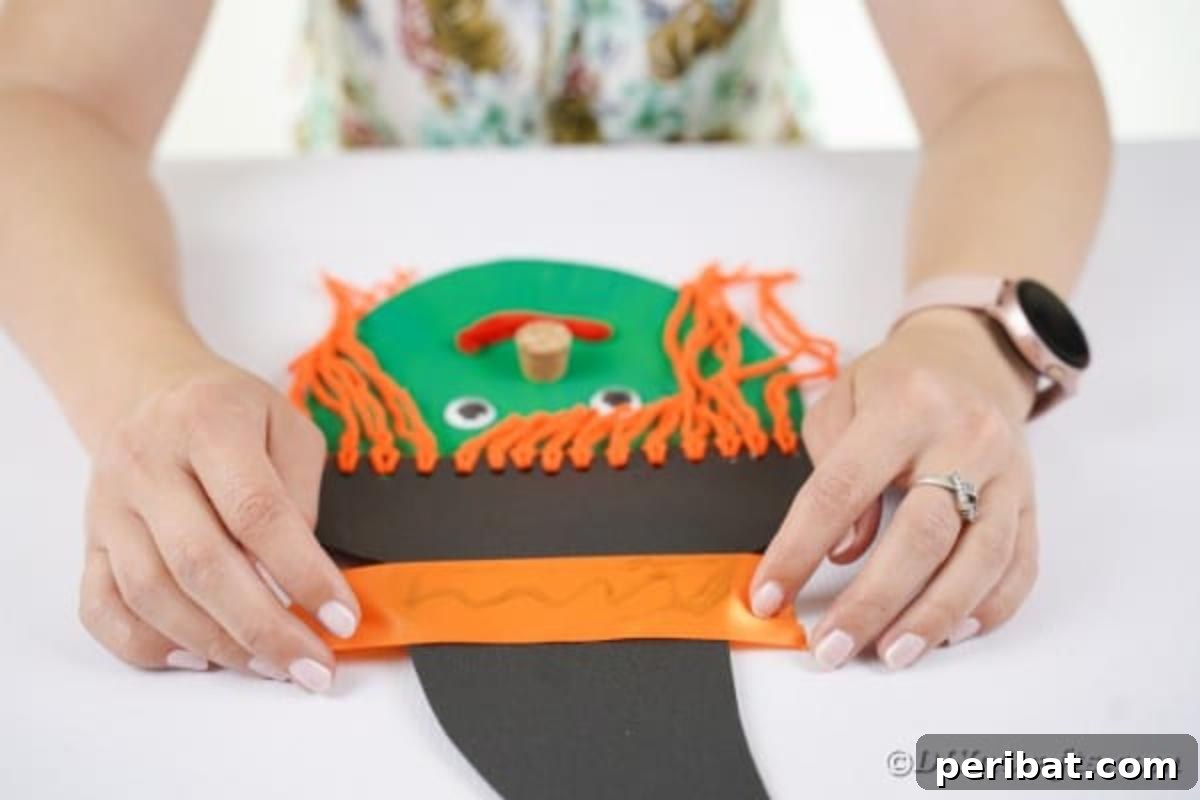 Spooktacular Paper Plate Witch Craft 19 Gluing an orange ribbon around the witch hat