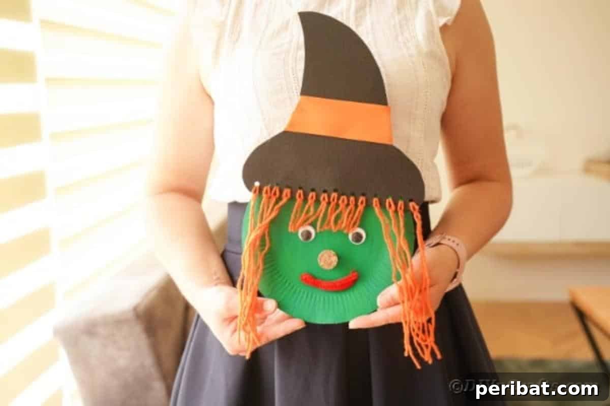Spooktacular Paper Plate Witch Craft 4 Person holding a finished paper plate witch craft