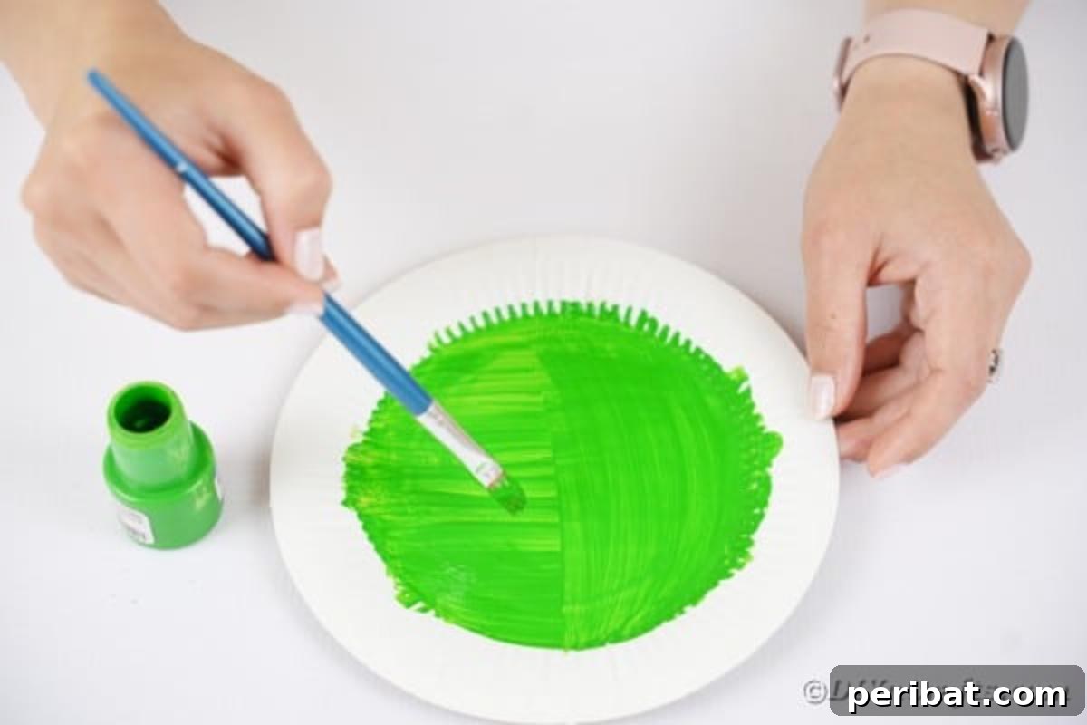 Spooktacular Paper Plate Witch Craft 8 Painting a paper plate green with a paintbrush