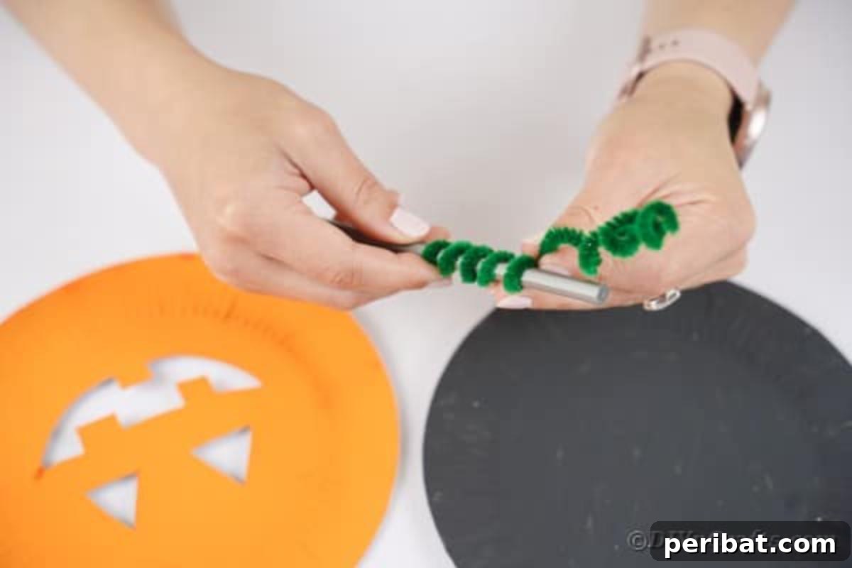 Grinning Gourd Lanterns: A Paper Plate Craft for Kids 12 Twisting a green pipe cleaner to create a spiral stem