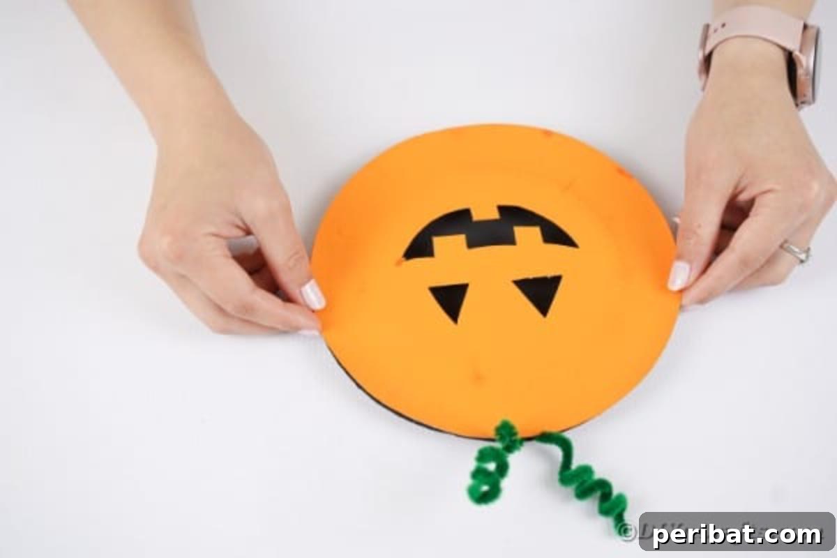 Grinning Gourd Lanterns: A Paper Plate Craft for Kids 14 Attaching the orange-painted plate on top of the black-painted plate
