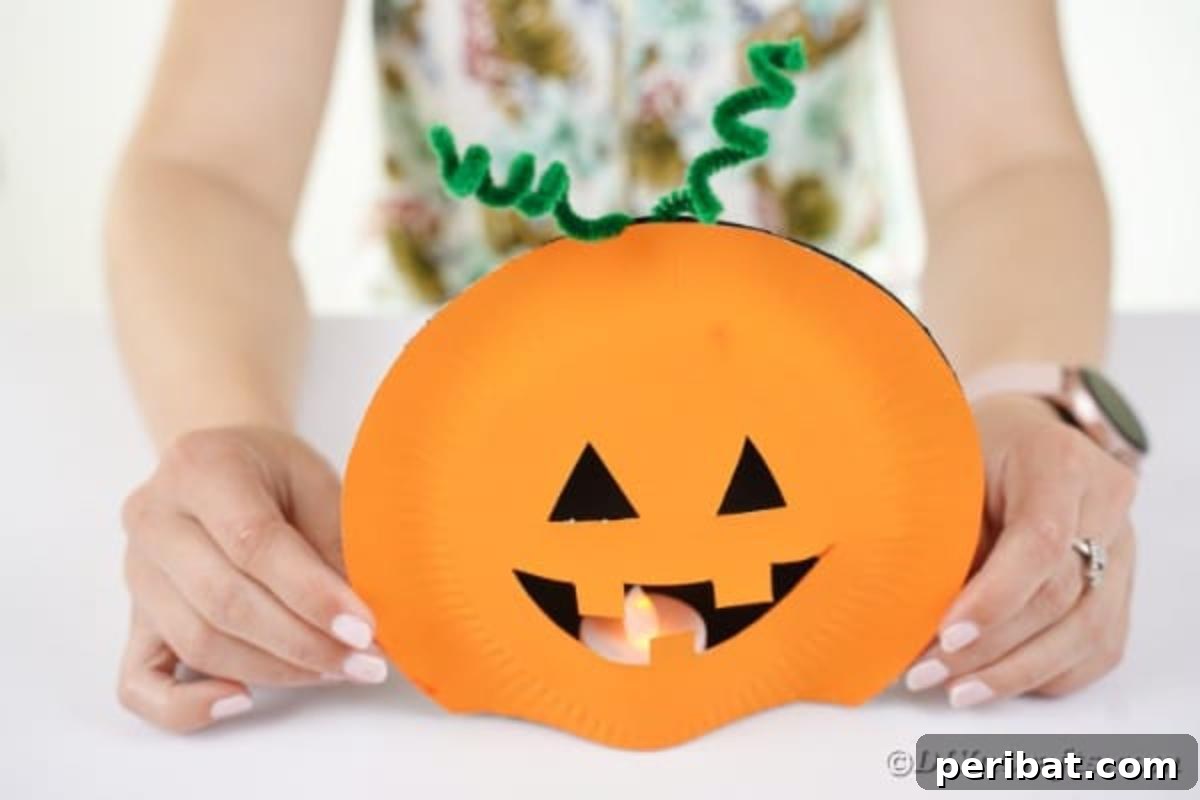 Grinning Gourd Lanterns: A Paper Plate Craft for Kids 16 Placing the assembled pumpkin plates over a flameless candle