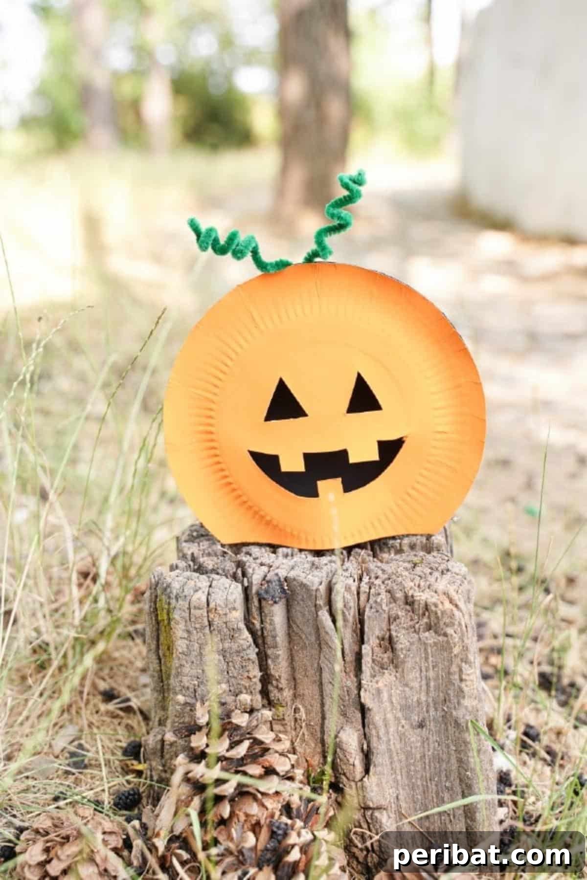 Grinning Gourd Lanterns: A Paper Plate Craft for Kids 26 Pumpkin craft resting on a tree stump in an outdoor setting