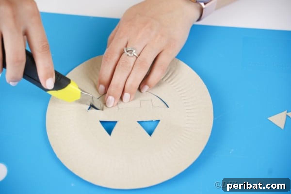 Grinning Gourd Lanterns: A Paper Plate Craft for Kids 10 Cutting out the traced face from the paper plate