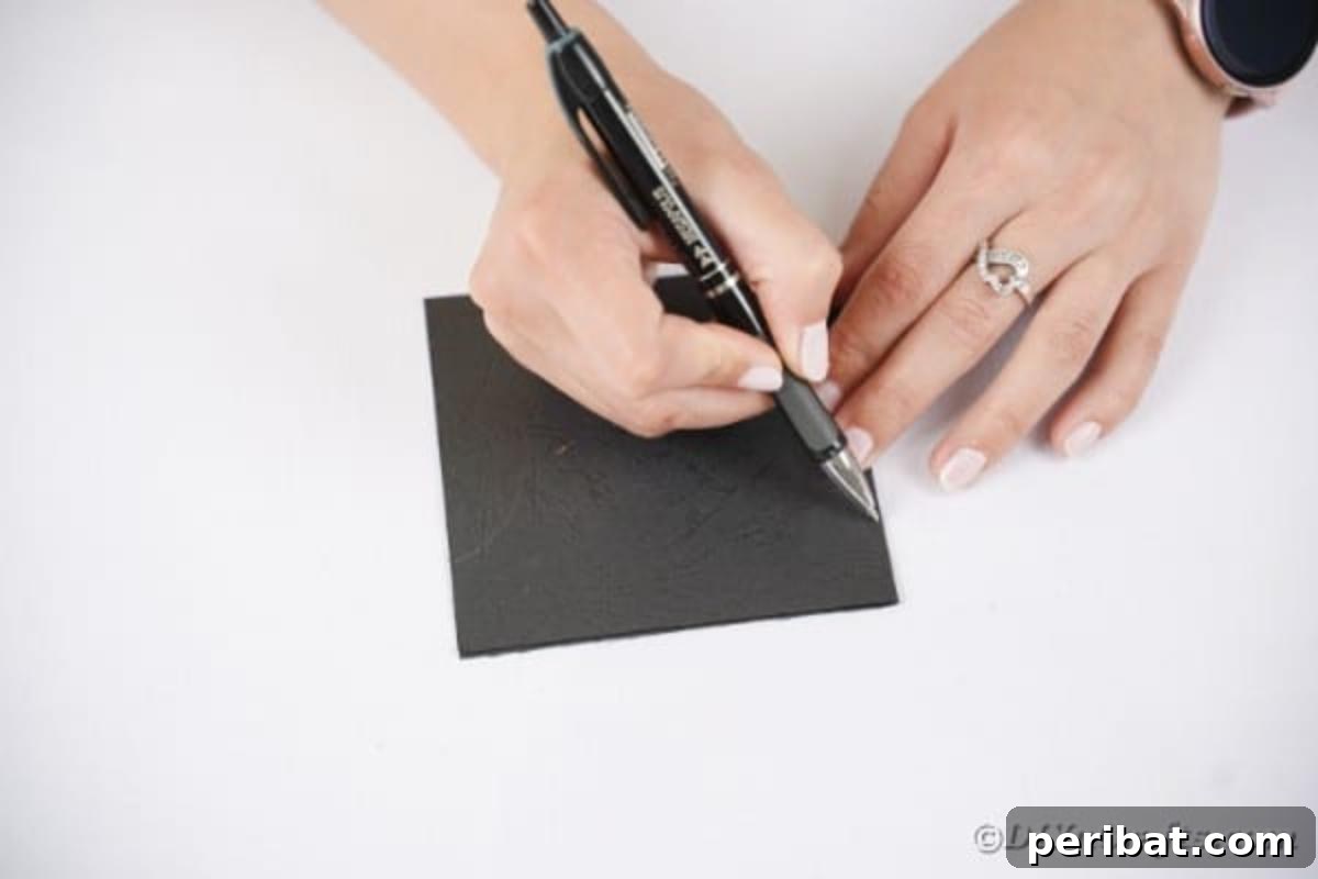 Adorable Recycled Plastic Spoon Bat Halloween Decor 10 A hand drawing a classic bat wing outline onto a sheet of black craft paper, preparing to cut out the shapes for the spoon bat craft.