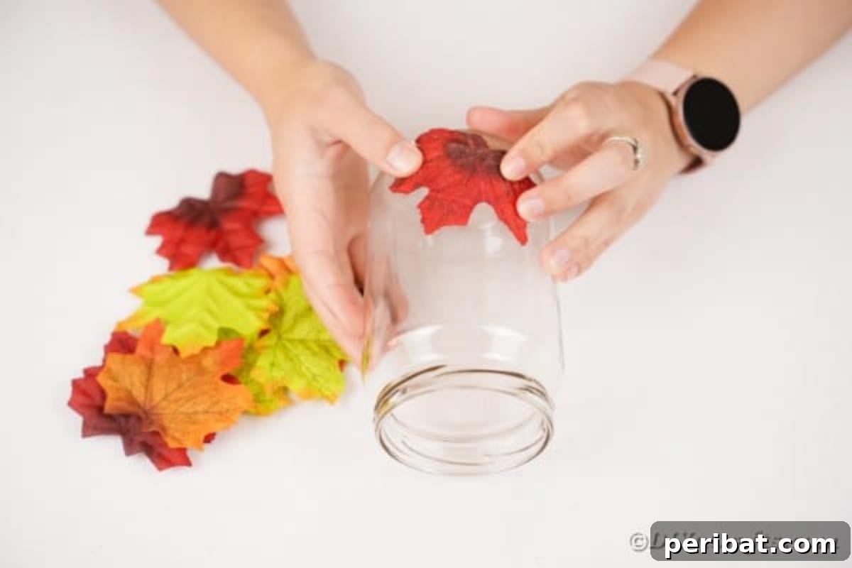 Autumn Leaf Jar Luminaries 12 Multiple glass jars, each adorned with a unique pattern of artificial fall leaves, showcasing the progress of decorating several lanterns simultaneously.