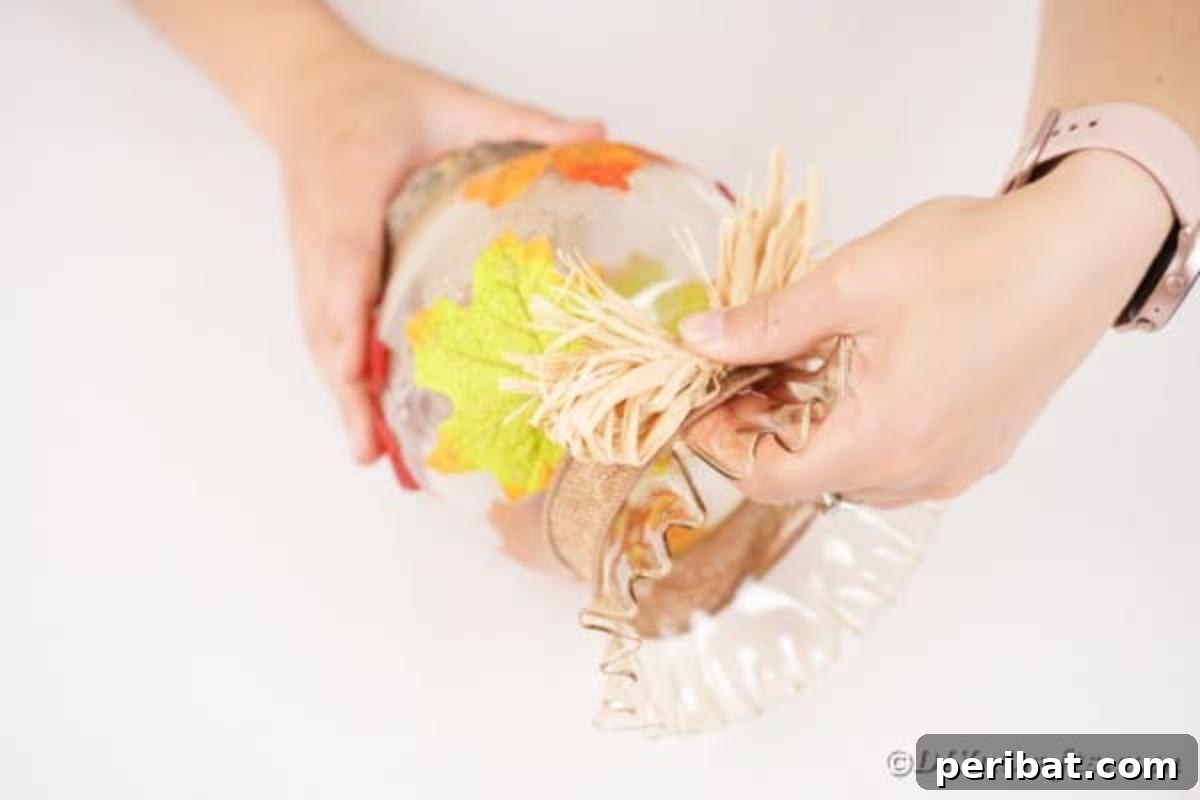 Autumn Leaf Jar Luminaries 14 Hands demonstrating how to tie a small, rustic bow with raffia, preparing it as a decorative embellishment for the fall lantern.