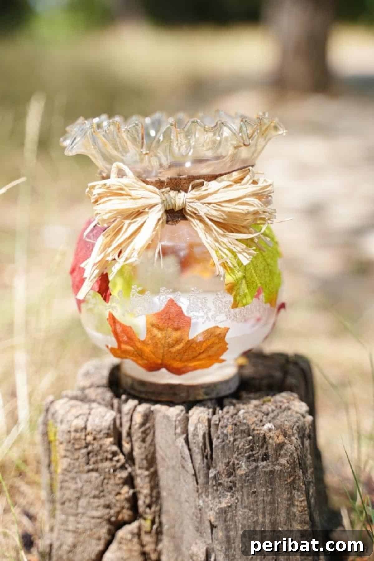 Autumn Leaf Jar Luminaries 21 A single glass fall lantern, artfully placed on a rustic tree stump outdoors, creating a charming and natural centerpiece.
