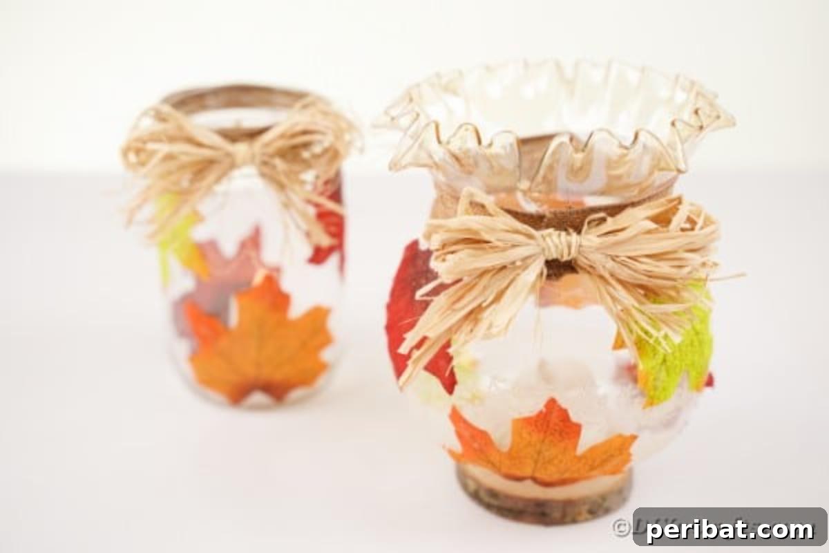 Autumn Leaf Jar Luminaries 7 A collection of fall leaf decorated jars, some illuminated, arranged gracefully on a pristine white table, highlighting their rustic elegance.