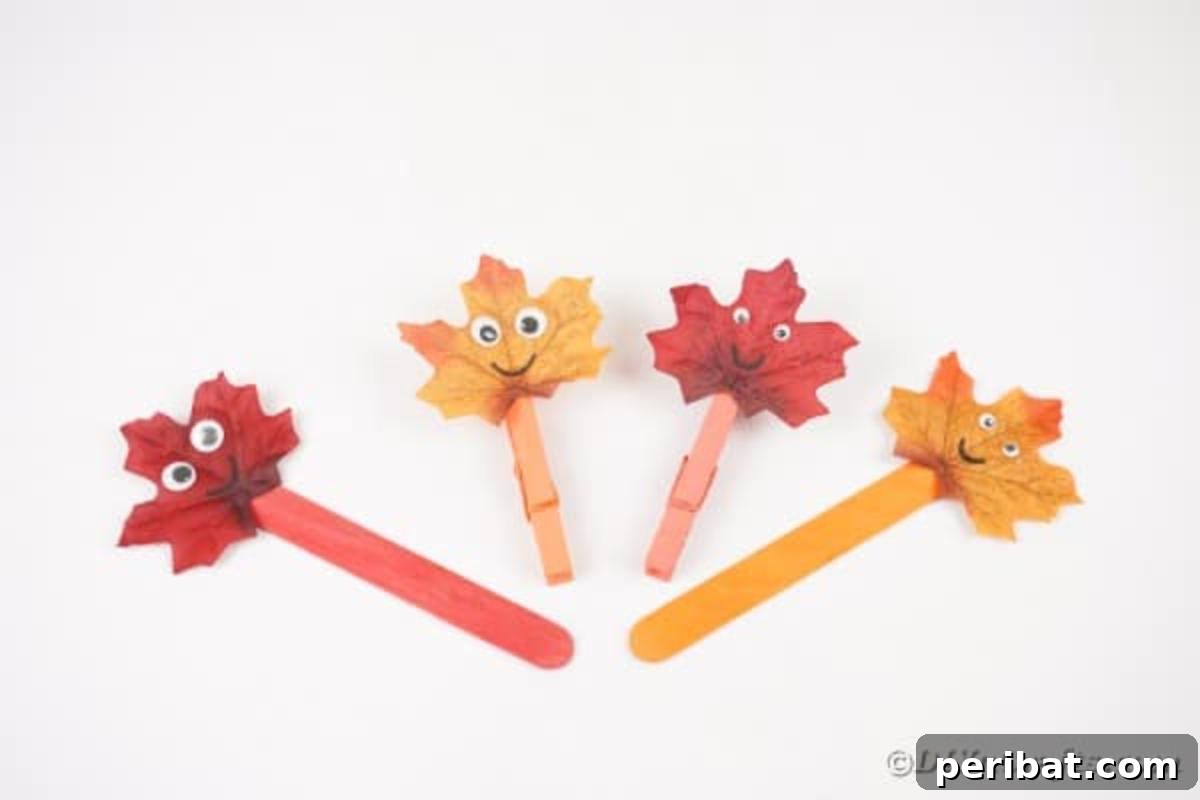 Geri Dönüşümle Sonbahar Yaprak İnsanlarını Canlandırın 15 Three completed fall leaf people crafts standing on a white table, showcasing their unique charm and readiness for display or play.