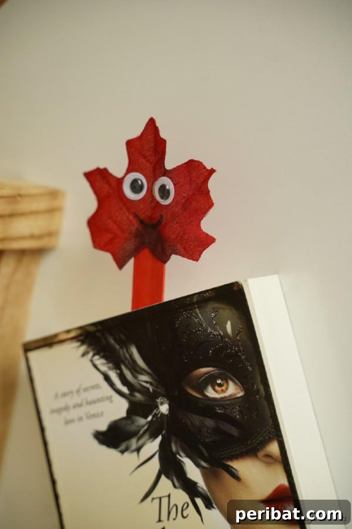 Geri Dönüşümle Sonbahar Yaprak İnsanlarını Canlandırın 16 A leaf person craft created from a craft stick being used as a bookmark in an open book, demonstrating one of its practical uses.