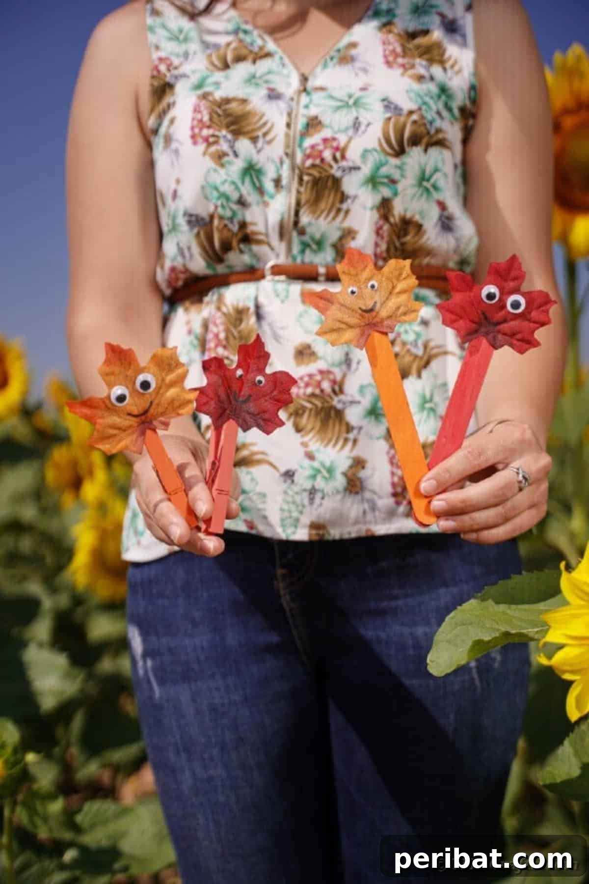 Geri Dönüşümle Sonbahar Yaprak İnsanlarını Canlandırın 17 A person holding two fall leaf people crafts made with clothespins, showcasing their use as fun, handheld characters.
