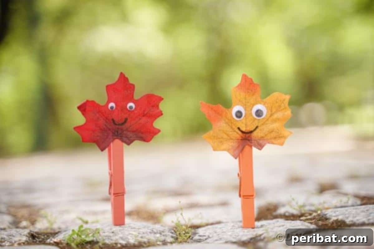 Geri Dönüşümle Sonbahar Yaprak İnsanlarını Canlandırın 3 A trio of leaf people crafts, one made with a craft stick and two with clothespins, standing on a textured surface, ready for play or display.