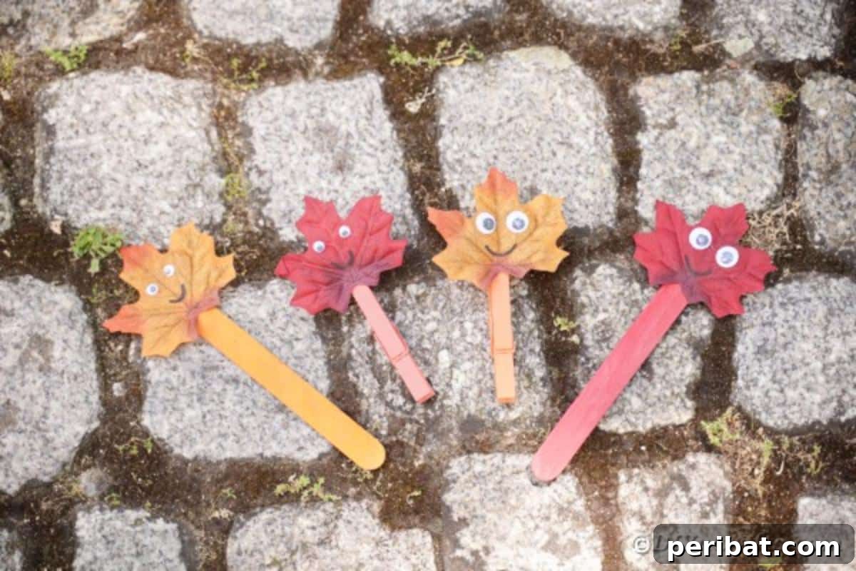 Geri Dönüşümle Sonbahar Yaprak İnsanlarını Canlandırın 4 Several fall leaf people crafts on a stone pathway, each with unique expressions and positions, ready for imaginative play.