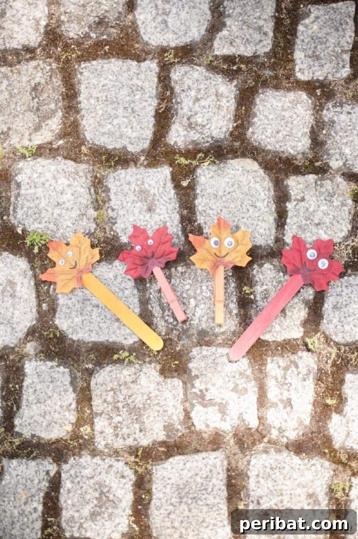 Geri Dönüşümle Sonbahar Yaprak İnsanlarını Canlandırın 20 A group of diverse fall leaf people crafts standing on an outdoor stone pathway, each with unique features, inviting creative play.