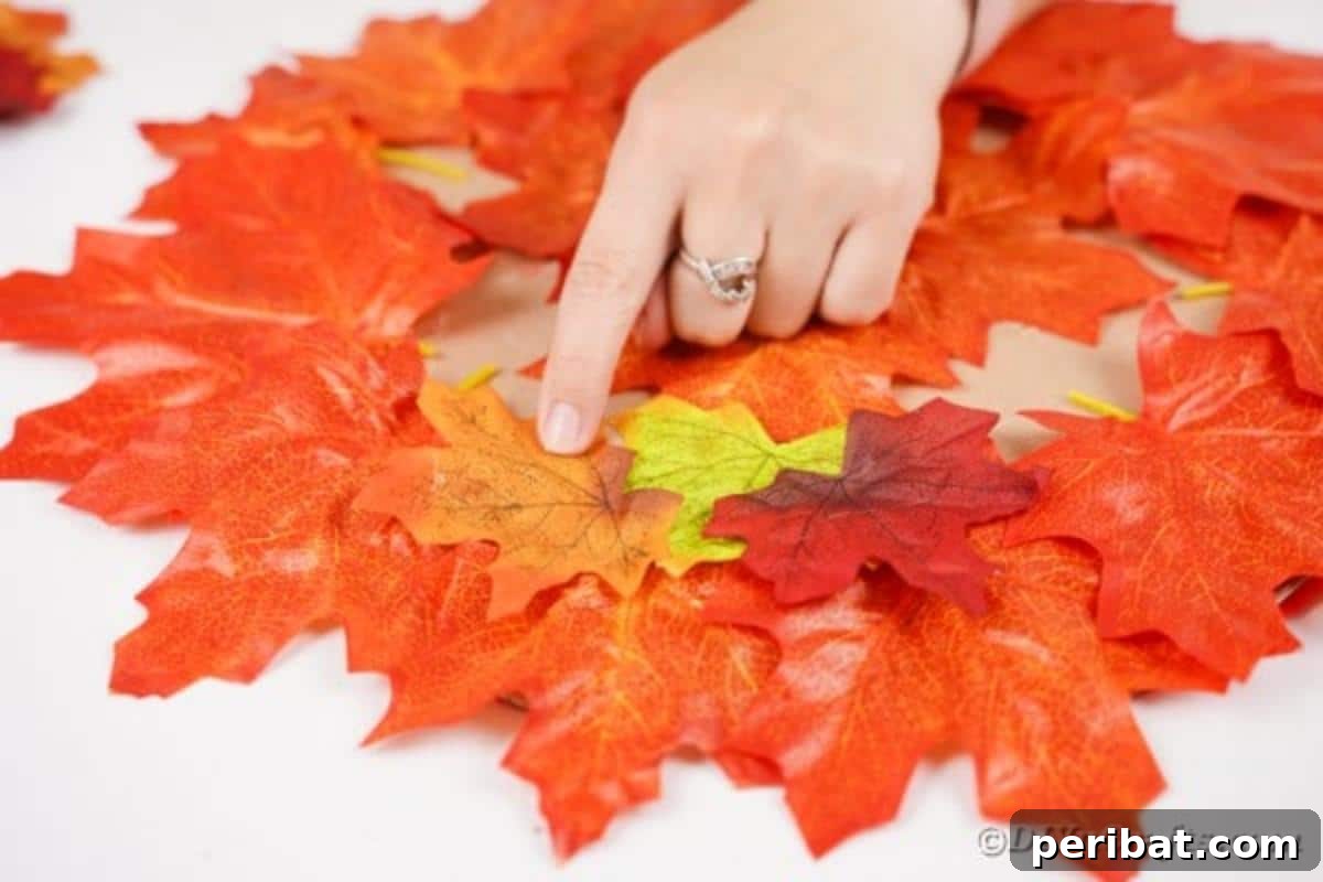 Continuously gluing layers of fall leaves to fully cover the circular cardboard placemat base