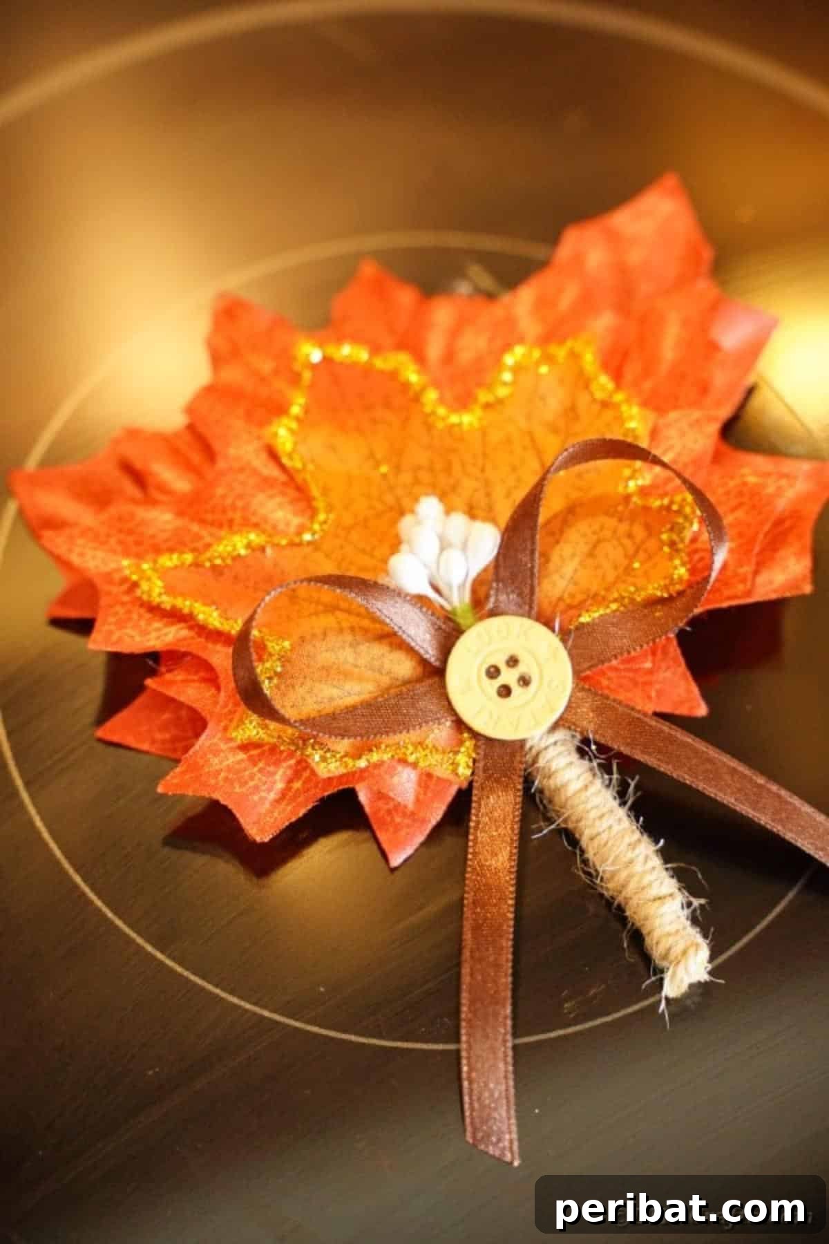 Elegant Autumnal Foliage Wedding Boutonnière 18 A beautifully crafted fall leaf boutonniere displayed on a dark stovetop, its vibrant colors and delicate glitter details catching the light.