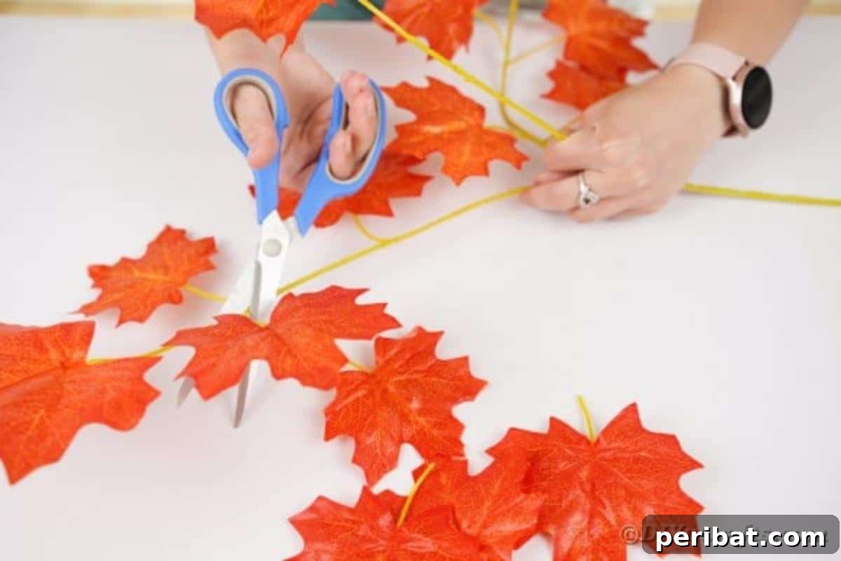 Elegant Autumnal Foliage Wedding Boutonnière 8 A hand cutting artificial leaves from a larger stem, carefully preparing them for the boutonniere assembly.