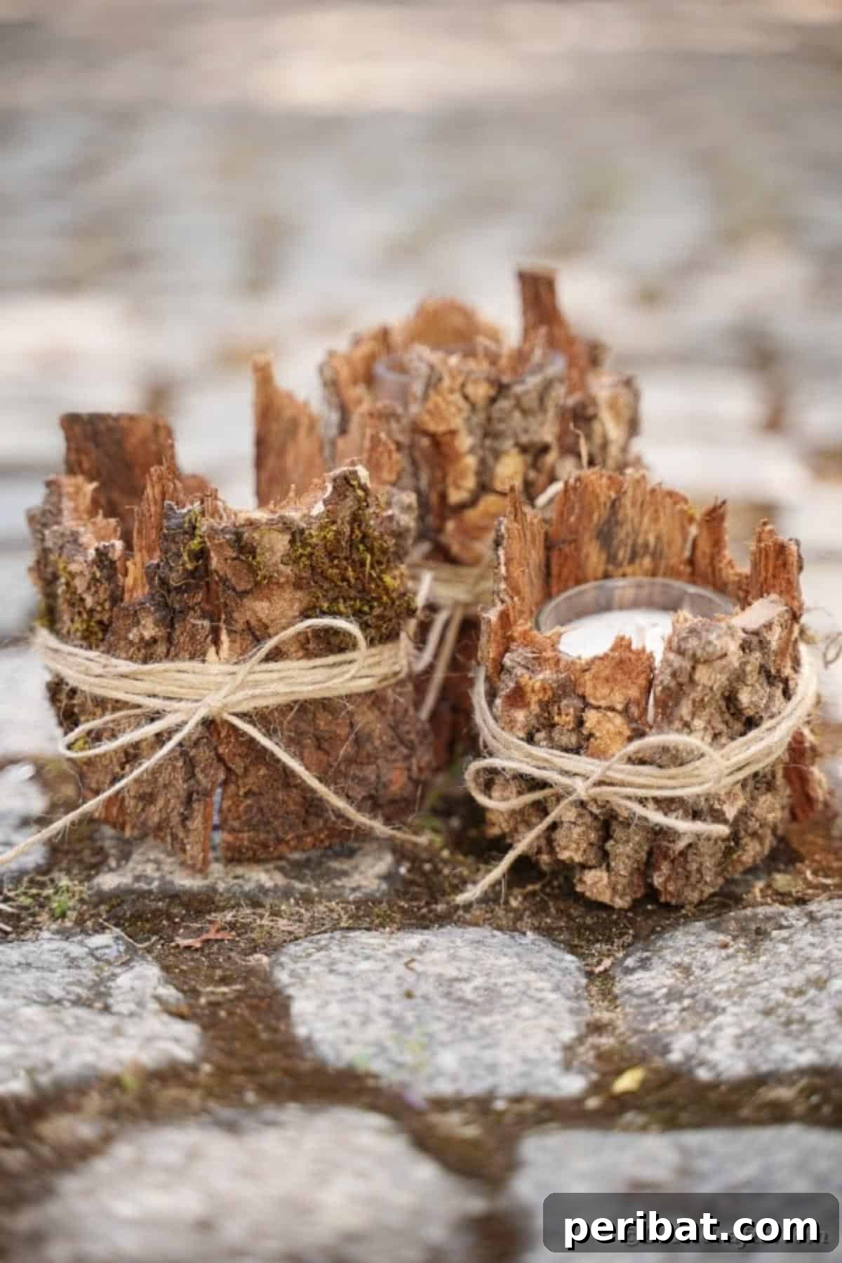 Woodland Hearth Bark Lantern 17 Three rustic tree bark lanterns grouped together on a cobblestone surface, illuminated softly