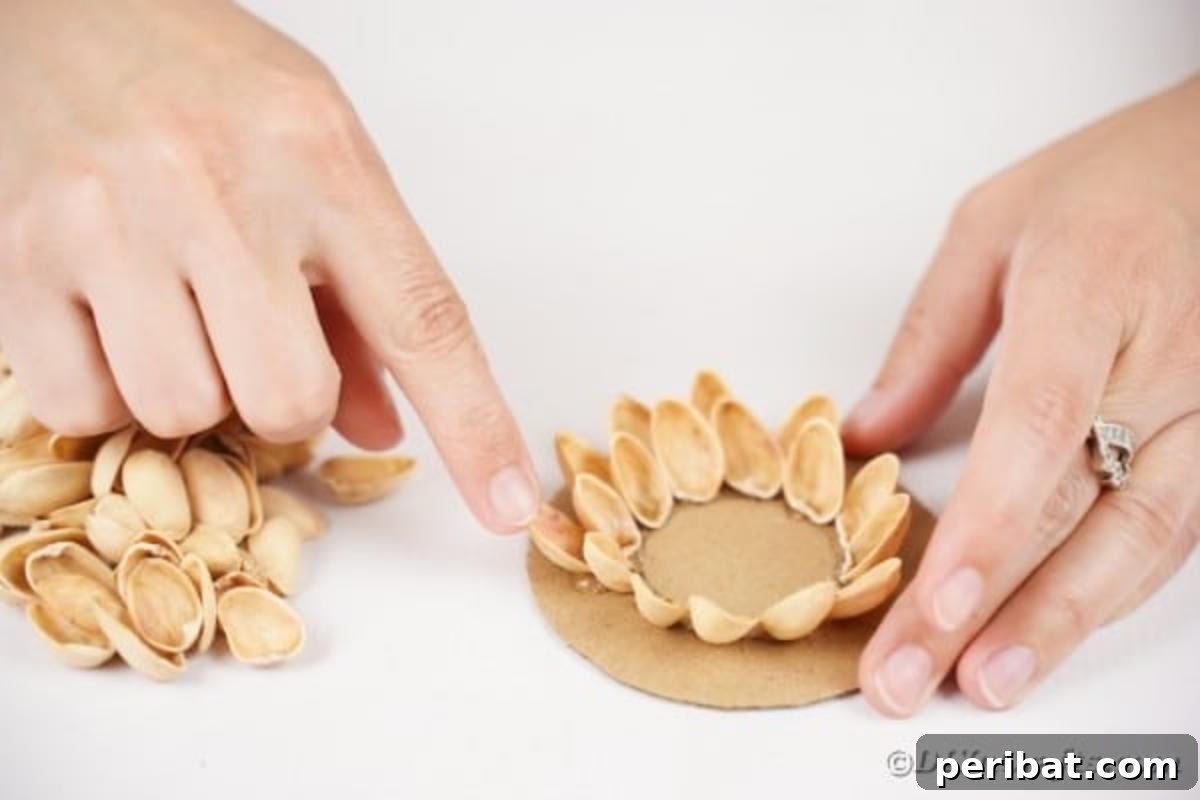 Artisanal Pistachio Shell Candle Holder 13 More pistachio shells being glued onto the cardboard base, building layers
