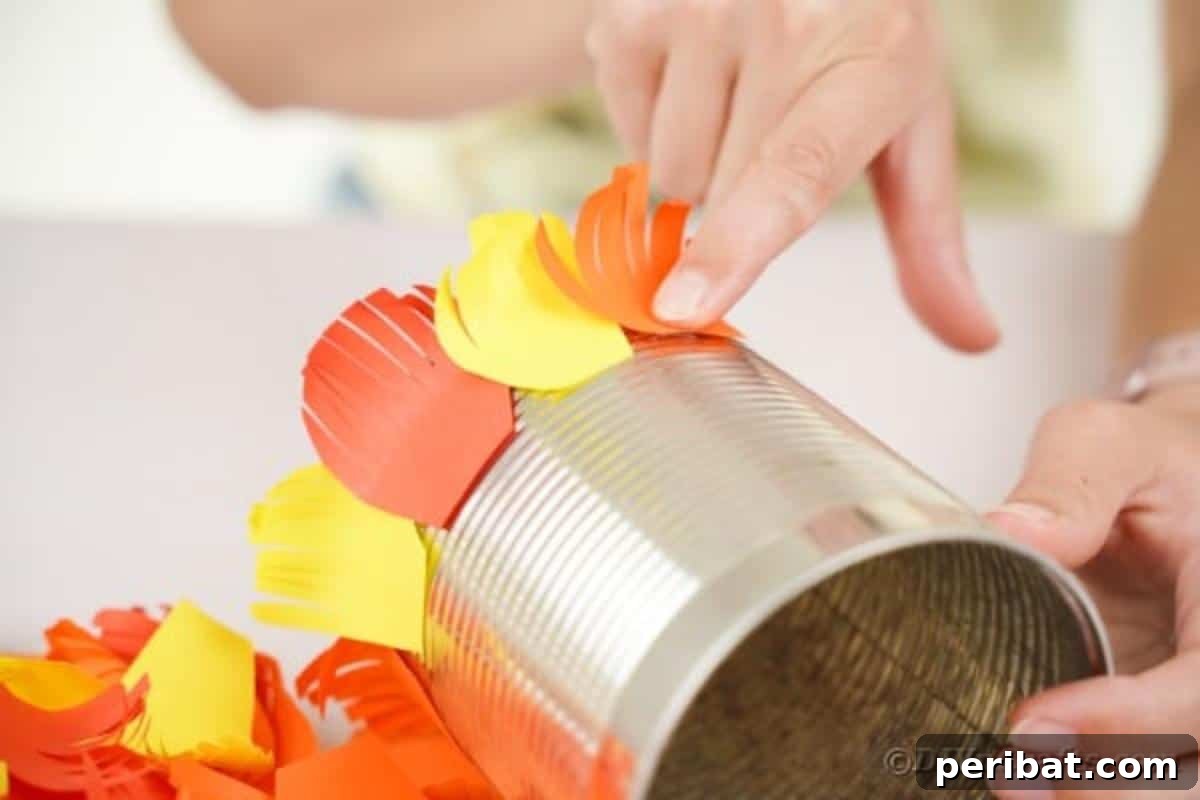 A tin can partially covered with colorful paper feathers, illustrating the progress of the feather application.