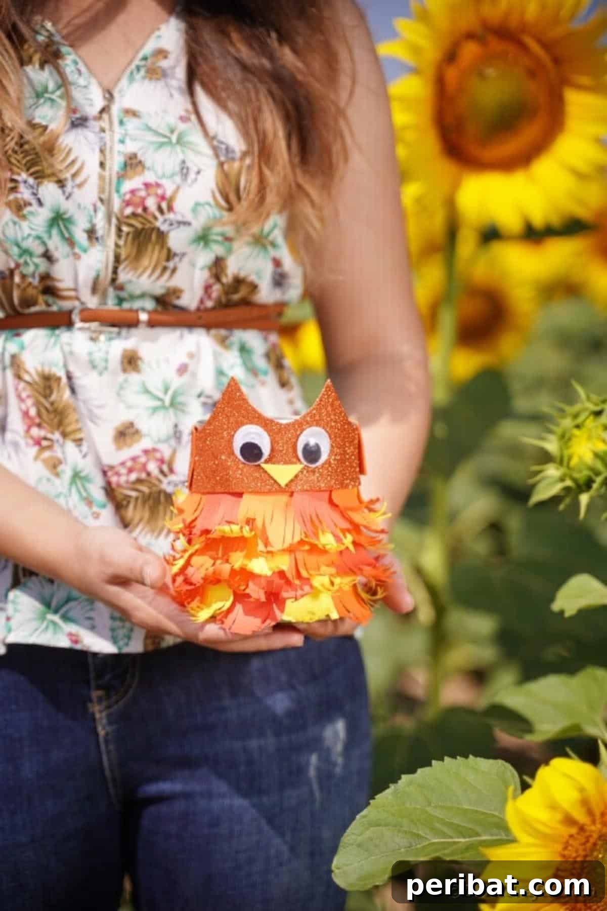 A woman holding the upcycled tin can owl, showcasing its full appearance as a charming fall decoration.