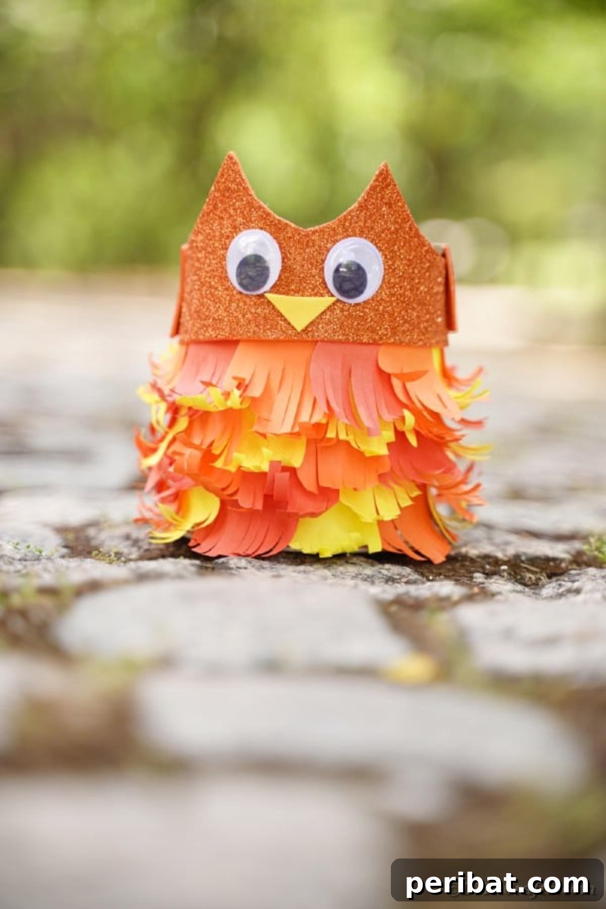 A woman holding a tin can owl, shown with potential legs at its base to increase its height for display.