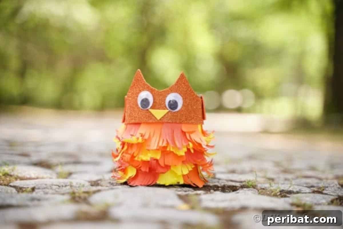 Upcycled tin can owl craft sitting on a cobblestone surface, highlighting its vibrant paper feathers and charming googly eyes.