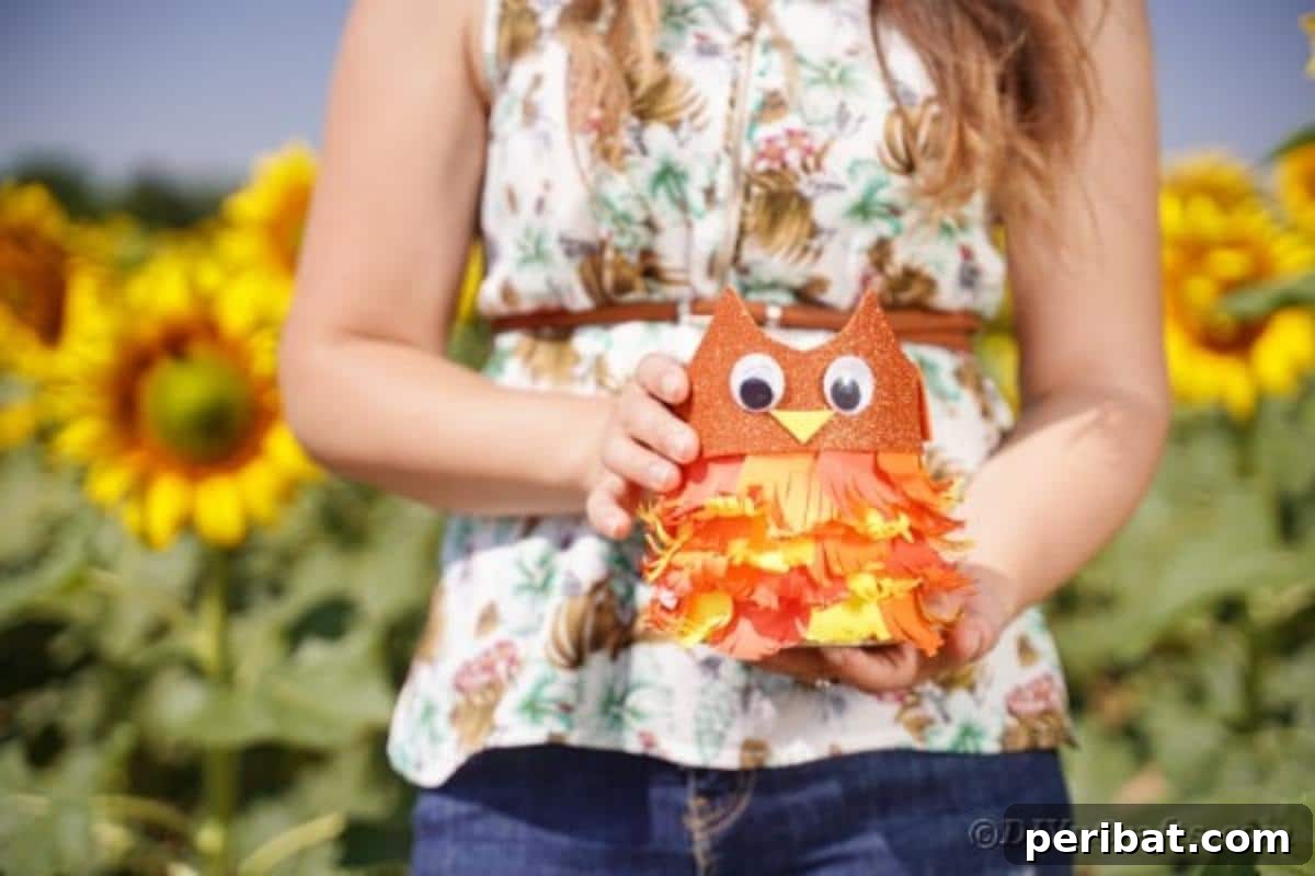 A hand holding the upcycled tin can owl craft against a blurred background, emphasizing its details.