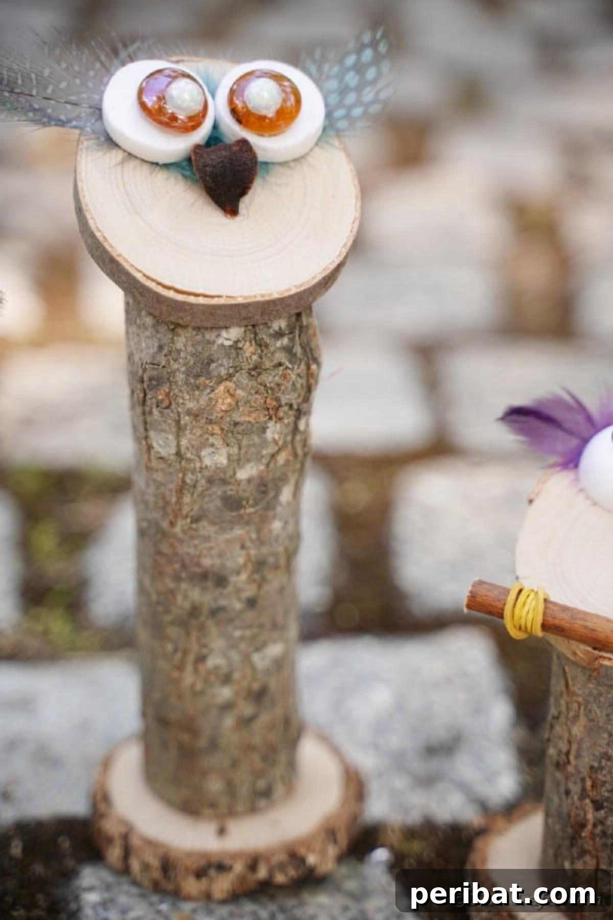 Whimsical Wooden Owls from Recycled Scraps Video Guide 19 A tall, elegantly simple wooden owl, crafted from natural wood and featuring a minimalist design, stands gracefully on a textured cobblestone background.